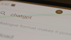 Close-up of a smartphone screen showing a search input field with the term 'chatgpt' typed in, along with a magnifying glass icon to the left and a front-facing camera at the top.